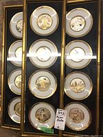 Three gilt bamboo-style frames each containing three white porcelain plates with gold rims and central Asian motifs