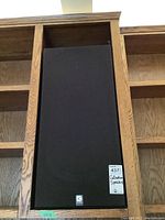 Front view of first speaker in oak shelving.