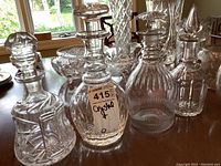 Four crystal decanters with various stopper designs and cut patterns on display