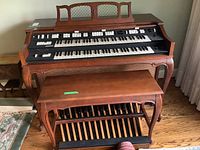 Front view of organ console with matching bench on hardwood floor