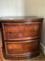 Front view of entire wood two-drawer file cabinet showing curved front and drawer faces.