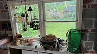 View of hanging bird feeders, wicker baskets, ceramic planters, and garden tools on windowsill.