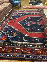 Large view of rug partially rolled up on hardwood floor with furniture