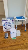 Full view of lot showing SoClean CPAP sanitizer, cartridge filter kits, Conair foot spa box, white tub chair with blue seat, and Wahl personal groomer in packaging
