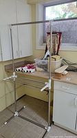Metal foldable clothes drying rack placed beside cabinet