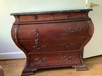 Front view of wooden cabinet showing three drawers with metal handles and marble top.