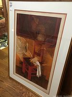 Full view of framed print leaning against wall on wood floor
