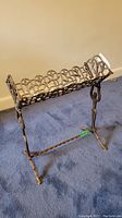 Full view of the solid iron book stand showing lattice pattern top and figure legs