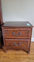 Front view of one wood side table showing two drawers with metal handles.
