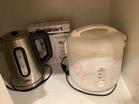 Photo of Oster electric kettle, National rice cooker, and Cuisinart hand mixer with box on shelf.