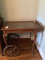 Side view of wood tea cart, showcasing large wooden wheels on one side and smaller caster wheels on the other.