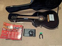 Overview of all items: guitar in open case with interface, USB cable, manual, box and wall hook