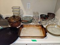 Photo showing large amber Pyrex covered casserole, clear glass plates, black round pan, and rectangular Pyrex baking dish.