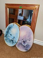Photo showing a square mirror with gold frame and two oval decorative wall hangers with child-themed illustrations in blue and purple.