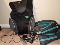 ObusForme neck and shoulder massager and truMedic chair massager pad shown on floor with power adapters and cords.