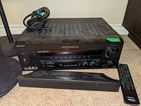 Sony STR-DE995 receiver with remote and sound bar in front, showing front panel details and controls.
