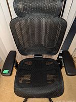 Close-up of seat and armrests showing black mesh material and armrest surfaces
