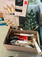 Green ceramic Christmas tree with clear light bulbs next to box of assorted holiday light bulbs
