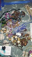 Photo of assorted multi-colored bead necklaces and bracelets on patterned surface.
