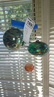 Three hanging glass balls arranged in front of a window.