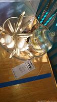 Glass bowl containing white starfish and multiple sea shells, with a glass decorative jar resting on the edge
