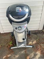 Front view of closed Char-Broil Patio Bistro grill showing black dome lid, silver handle, wheels, and front control panel.