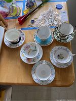 Photo of six teacup and saucer sets arranged on a table, showing diverse floral patterns and styles.