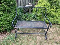 Front view of black metal bench with heart-shaped scroll back