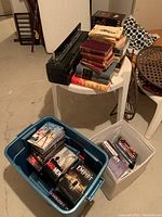 Wide shot of plastic table with stacked books and two tubs containing DVD and CD cases and prints