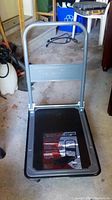 Folding dolly by Olympia Tools, showing the metal frame handle and platform base