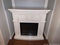 Front view of white electric fireplace with decorative mantel, showing fireplace opening and lower base.
