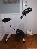 Left side view of the Impex-Marcy foldable exercise bike showing seat, pedals, digital display, and frame.