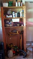 Photo of shelving unit showing various bottles of liquids, garden chemicals, and some hand tools hanging on the side