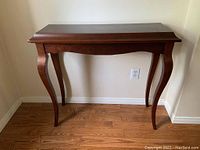 Front view of the wooden hallway table showing curved legs and tabletop surface.