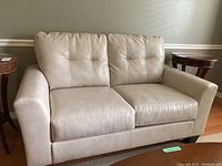 Front view of light beige DuraBlend leather loveseat with tufted back cushions and two seat cushions.