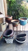 Overview of all planters and plant stands outdoors with greenery in background