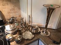 Full lot shot showing all silverplate items including vase, multiple serving dishes, butter dish, candleholders, trinket box, sauce boat, cream and sugar, salt and pepper, and christening cup.