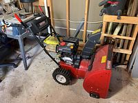 Side-angle of snowblower showing auger housing, chute and control handles
