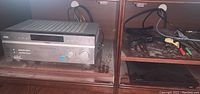 Sony STR-DE598 FM Stereo Receiver and Sony BDP-S1200 Blu-ray DVD Player placed side by side on wooden shelving, with cables atop receiver.