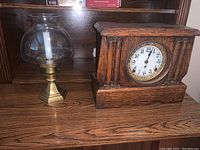 Clock and lamp side by side on wooden surface