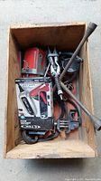 Wooden crate containing various automotive tools including tire iron, clamps, and a red tool.