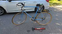 Full side view of blue Raleigh Record bicycle with yellow rimmed wheels, rear rack and pump visible below frame