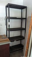 Full view of the black plastic collapsible shelving unit with five shelves.