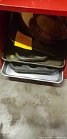 Stack of metal cookie sheets and pans, visibly three to four pieces including a textured pie pan on top