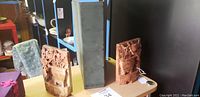 Pair of oriental style carved book ends shown upright on a table with a green box between them