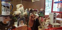 Wide shot of Christmas-themed ornaments, singing figurines, and mugs displayed on a shelf.