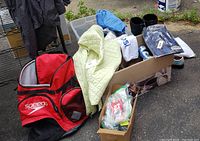 Wide view showing Speedo backpack, woman's green quilted vest, various clothing items and boxes
