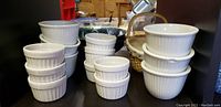 Eight white ribbed ceramic ramekins stacked, one chipped visible