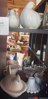 Photo showing white hobnail milk glass bird-shaped covered dish and white hobnail hen figurine with nearby decorative glass bowls and mugs.