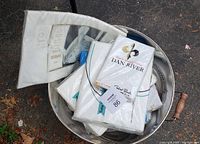 View showing various packaged linens inside a metal tub, including visible brand label 'Dan River'.